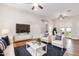 Open living room area with hardwood floors, modern white furniture, TV, and ceiling fans at 4205 E Edgemont Ave, Phoenix, AZ 85008