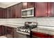 Kitchen with stainless steel oven and microwave, dark wood cabinets, and tile backsplash at 4102 S 186Th Ave, Goodyear, AZ 85338