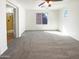 This spacious bedroom features plush gray carpeting, a ceiling fan, and natural light from two windows at 1948 W Busoni Pl, Phoenix, AZ 85023