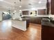 Open kitchen with dark wood cabinets, granite countertops, a white island, and stainless steel appliances at 1948 W Busoni Pl, Phoenix, AZ 85023