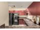 Kitchen with stainless steel appliances, granite countertops, and maroon colored wood cabinets at 114 W Adams St # 506, Phoenix, AZ 85003