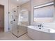 Modern bathroom featuring a glass-enclosed shower, sleek soaking tub, and a large window offering natural light at 23978 S 218Th Pl, Queen Creek, AZ 85142
