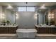 Elegant bathroom featuring dual vanities, a modern soaking tub, decorative lighting, and a large window at 37200 N Cave Creek Rd # 1023, Scottsdale, AZ 85262
