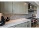 Stylish kitchen featuring white countertops, tiled backsplash, stainless steel hood, and light green cabinets at 37200 N Cave Creek Rd # 1023, Scottsdale, AZ 85262