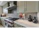 Modern kitchen with a stainless hood vent, gas cooktop with red knobs, and white countertop at 37200 N Cave Creek Rd # 1023, Scottsdale, AZ 85262