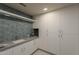 Laundry room featuring a sink, white cabinetry, and stylish blue tile at 37200 N Cave Creek Rd # 1023, Scottsdale, AZ 85262