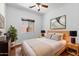 Tastefully decorated bedroom with modern furniture, ceiling fan, wood-look floors, and natural lighting at 44032 W Garden Ln, Maricopa, AZ 85139