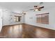Empty living room with wood floors, three windows, and two ceiling fans at 44032 W Garden Ln, Maricopa, AZ 85139