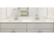 Contemporary double sink vanity with sleek chrome fixtures and a large mirror reflecting the closet at 15995 W Cottontail Ln, Surprise, AZ 85387