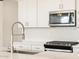 Close up of new stainless steel microwave and gas range with white backsplash and stone countertops at 15995 W Cottontail Ln, Surprise, AZ 85387