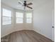 Bedroom with wood floors, ceiling fan, and three windows allowing for natural light at 43594 W Bravo Ct, Maricopa, AZ 85138