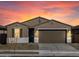 This single-story home stands out with warm lighting and a colorful sunset backdrop at 16034 W Desert Hollow Dr, Surprise, AZ 85387