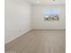 Bright bedroom featuring light wood floors, white walls, and a window at 16062 W Prickly Pear Trl, Surprise, AZ 85387