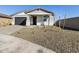 Attractive home exterior with a gravel front yard and young trees, showcasing modern design at 16062 W Prickly Pear Trl, Surprise, AZ 85387