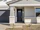 Close-up of the front entrance featuring a stylish black door, stone accents, and a covered porch at 16062 W Prickly Pear Trl, Surprise, AZ 85387