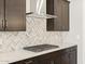 Detailed view of the kitchen with dark cabinets, stainless steel vent hood, and cooktop at 4832 N 177Th Dr, Goodyear, AZ 85395