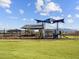 Community playground with modern play structure on a green lawn under a partly cloudy sky at 4862 N 177Th Dr, Goodyear, AZ 85395