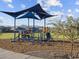 Community playground featuring covered play structure with slides, climbing nets, and monkey bars, surrounded by lush green grass at 4862 N 177Th Dr, Goodyear, AZ 85395