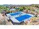 Aerial view of pristine blue and grey tennis courts surrounded by desert landscape and lush greenery at 2740 W Plum Hollow Dr, Anthem, AZ 85086