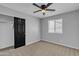 Carpeted bedroom featuring a ceiling fan, window, and a closet with black sliding doors at 10810 W Torren Dr, Arizona City, AZ 85123