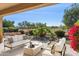 A covered patio with stylish outdoor furniture and a view of the landscaped backyard and desert scenery at 12377 W Running Deer Ct, Peoria, AZ 85383