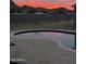 Outdoor pool with a stone deck and a vivid sunset reflecting off the water at 16244 N 21 St, Phoenix, AZ 85022