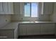 Well-lit laundry room featuring white cabinets and counters, complete with a window for natural light at 1907 W Brooke Ln, Queen Creek, AZ 85144