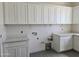 Bright laundry room featuring white cabinetry and countertops, complemented by wood-look flooring at 1907 W Brooke Ln, Queen Creek, AZ 85144