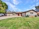 Charming single-story home with mature landscaping, green lawn, and a welcoming red front door at 8450 E Montecito Ave, Scottsdale, AZ 85251