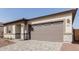 Attached two-car garage featuring a neutral color, and gray brick paver driveway at 17594 W Blue Sky Dr, Surprise, AZ 85387