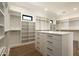 Spacious walk-in closet featuring custom shelving, drawers and a center island with bright modern lighting at 28171 N 95Th St, Scottsdale, AZ 85262