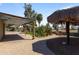 Well-maintained backyard featuring brick pavers, tiki huts, lush greenery, and decorative accents at 848 S Revolta Cir, Mesa, AZ 85208