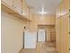 Well-lit laundry room features bright wood cabinets, washer, dryer, and travertine tile flooring at 848 S Revolta Cir, Mesa, AZ 85208
