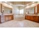 Luxurious bathroom with dual vanities, a jetted tub with travertine surround, and travertine floors at 19517 W Huron Ln, Buckeye, AZ 85326