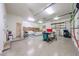 Well-lit garage with speckled floors, pegboard wall, overhead shelving, and work tables at 19517 W Huron Ln, Buckeye, AZ 85326