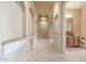 Hallway featuring travertine floors and arched doorways, leading to a well-appointed bathroom with a vessel sink at 19517 W Huron Ln, Buckeye, AZ 85326