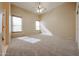 Spacious carpeted bedroom with a ceiling fan and natural light from two windows at 19517 W Huron Ln, Buckeye, AZ 85326