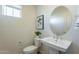 Well-lit powder room with a pedestal sink, modern fixtures, and a decorative mirror for added style and elegance at 2200 N Iowa St, Chandler, AZ 85225