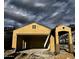 Unfinished single-Gathering home features a Spanish-tile roof and an open garage under a cloudy sky at 5656 N 205Th Ln, Buckeye, AZ 85396