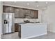 Modern kitchen featuring stainless steel appliances, a center island with a sink, and stylish dark wood cabinetry at 24620 W Hopi W St, Buckeye, AZ 85326