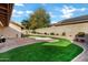 Landscaped backyard with artificial turf, brick patio, and heart-shaped design at 9478 E Corrine Dr, Scottsdale, AZ 85260