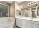 Bright bathroom with a double sink vanity, a large mirror, and a tub near the window at 14859 W Surrey Dr, Surprise, AZ 85379