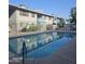 Community swimming pool surrounded by condos, chairs and tables, and metal fence at 2608 W Berridge Ln # 220, Phoenix, AZ 85017
