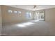 Spacious, carpeted living room with bright, natural light and a ceiling fan at 27174 N 85Th Dr, Peoria, AZ 85383