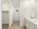 Bathroom featuring double sinks, neutral walls and tile flooring with a walk-in closet to the left at 16038 W Desert Hollow Dr, Surprise, AZ 85387