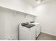 Laundry room with a modern washer and dryer, and additional shelving at 16038 W Desert Hollow Dr, Surprise, AZ 85387