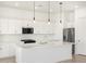 Modern white kitchen featuring an island, stainless steel appliances, and stylish pendant lighting at 17672 W Pierson St, Goodyear, AZ 85395