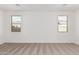 Spacious bedroom with neutral carpeting and two windows at 18350 W Poston Dr, Surprise, AZ 85387