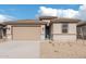 One-story home with tan exterior, two-car garage, and landscaped front yard at 18350 W Poston Dr, Surprise, AZ 85387