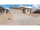 Newly built home with tan exterior, two-car garage, and desert landscaping at 18350 W Poston Dr, Surprise, AZ 85387